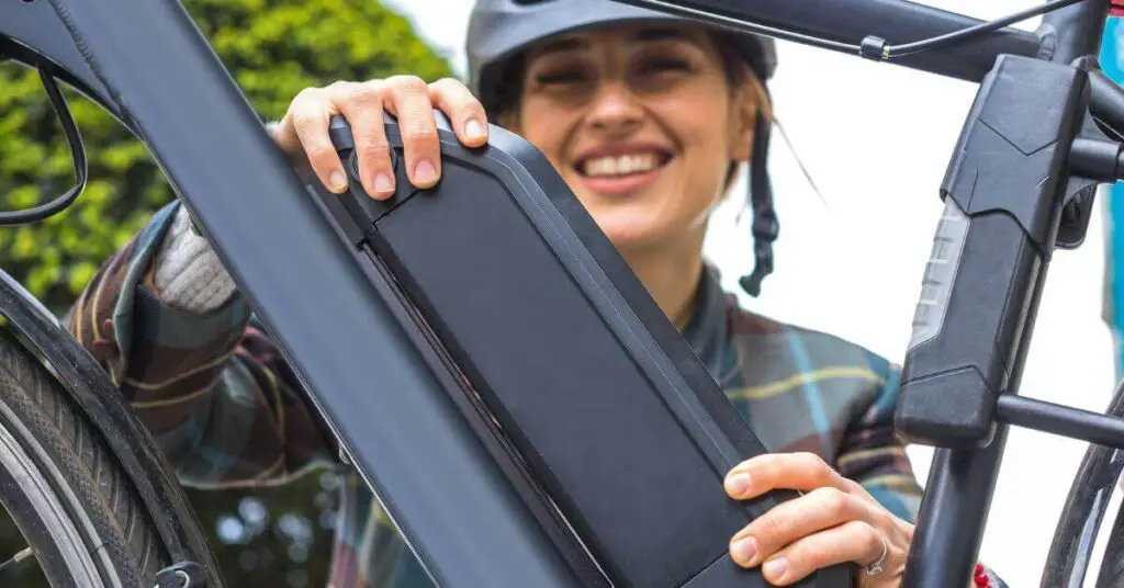 IMAGE OF A WOMAN INSTALLING HER ELECTRIC BIKE'S BATTERY